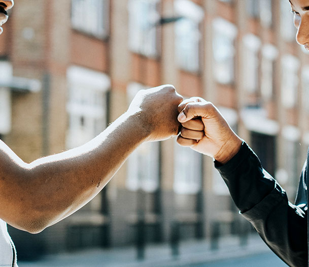 image of 2 people fist bumping on the street
